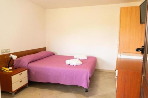two beds in a room with purple sheets and towels at Hotel Palinuro Cilentiamoci rooms in Palinuro