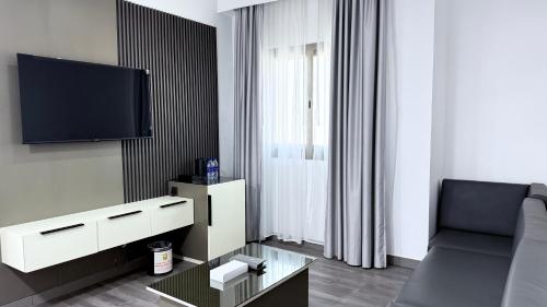 a living room with a couch and a tv at Royal Tulip Dancenter Suites Sharjah in Sharjah