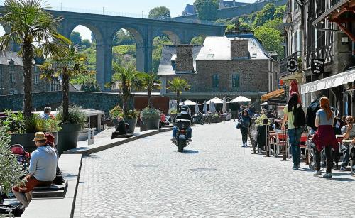 una strada con persone che camminano e un uomo in sella a una motocicletta di La Maison des Cordiers a Dinan