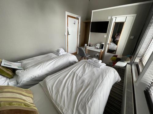 a hotel room with two beds and a mirror at The Mowbray in Eastbourne