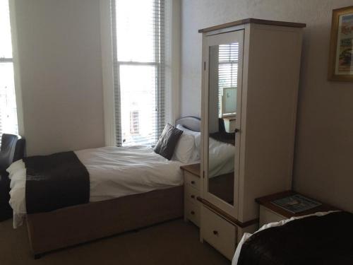a bedroom with a bed and a dresser with a mirror at The Mowbray in Eastbourne