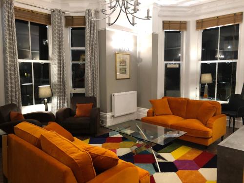 a living room with orange furniture and windows at The Mowbray in Eastbourne