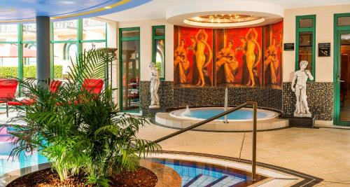 a lobby with a hot tub and paintings on the wall at Victor's Residenz-Hotel Schloss Berg in Nennig
