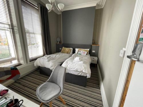 two beds in a small room with a chair at The Mowbray in Eastbourne