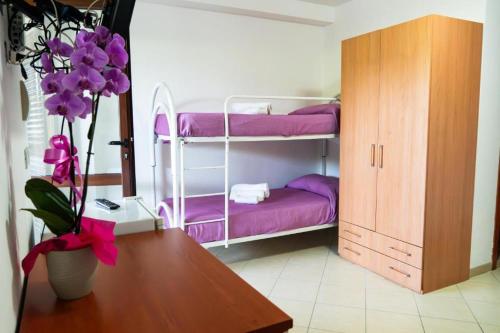 a room with two bunk beds with purple sheets at Hotel Palinuro Cilentiamoci rooms in Palinuro