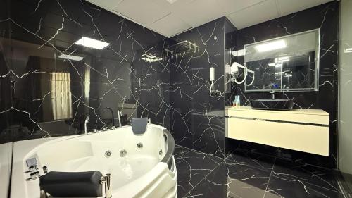 a bathroom with a white tub and a black wall at Royal Tulip Dancenter Suites Sharjah in Sharjah