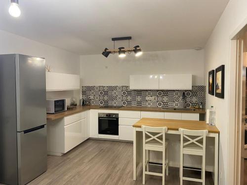 a kitchen with white cabinets and a table and a refrigerator at Appartement plein centre à 50m de la plage in Soulac-sur-Mer