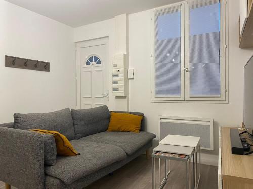 a living room with a gray couch and a window at Appartement plein centre à 50m de la plage in Soulac-sur-Mer