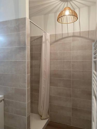 a shower with a shower curtain and a light at Appartement plein centre à 50m de la plage in Soulac-sur-Mer