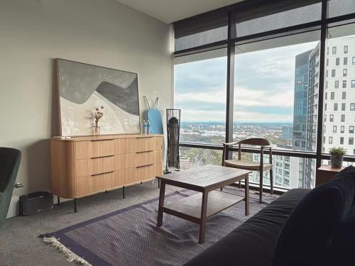 a living room with a table and a large window at Luxury Sky Escape in Sydney Olympic Park in Sydney