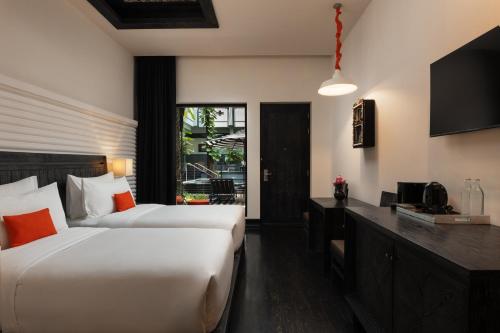 a hotel room with two beds and a television at Shinta Mani Angkor in Siem Reap