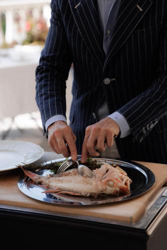 a man is cutting a fish on a plate at Hotel Villa La Bollina in Serravalle Scrivia