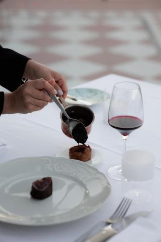 a person is serving food on a table with a glass of wine at Hotel Villa La Bollina in Serravalle Scrivia