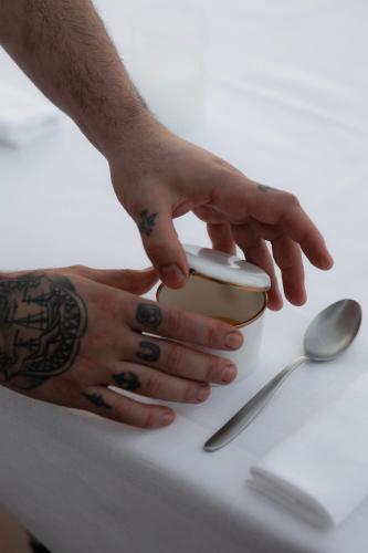 a man with tattoos on his hands holding a cup on a table at Hotel Villa La Bollina in Serravalle Scrivia