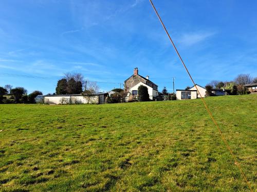 ein grünes Feld mit einem Haus im Hintergrund in der Unterkunft Bell Tent 2 in St Austell