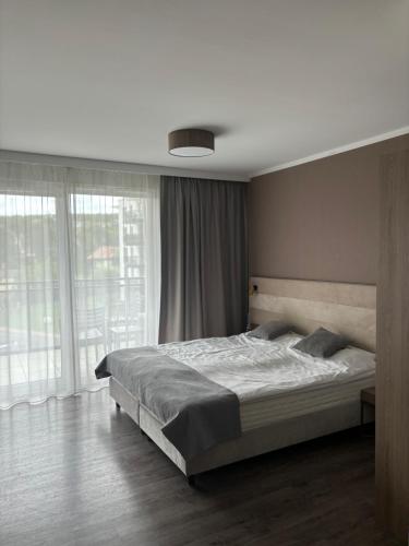 a bedroom with a bed and a large window at Apartament e310 - Bel Mare Międzyzdroje in Międzyzdroje