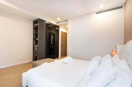 a bedroom with a white bed with white pillows at Lumiere Riverside Heera Stay Apartment in Ho Chi Minh City
