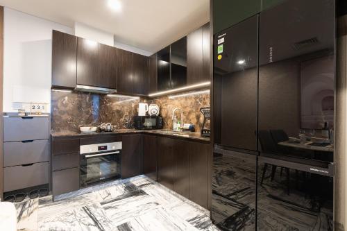 a kitchen with dark wood cabinets and a sink at Lumiere Riverside Heera Stay Apartment in Ho Chi Minh City