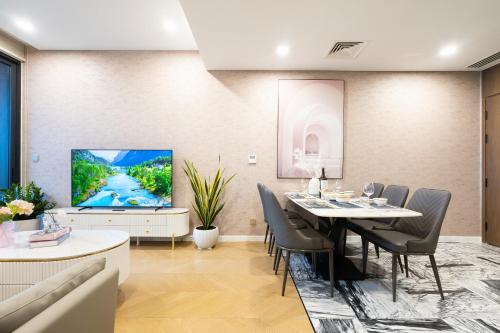 a dining room with a table and chairs and a tv at Lumiere Riverside Heera Stay Apartment in Ho Chi Minh City