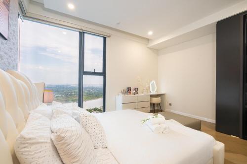 a bedroom with a white bed and a large window at Lumiere Riverside Heera Stay Apartment in Ho Chi Minh City