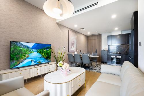 a living room with a white couch and a tv at Lumiere Riverside Heera Stay Apartment in Ho Chi Minh City