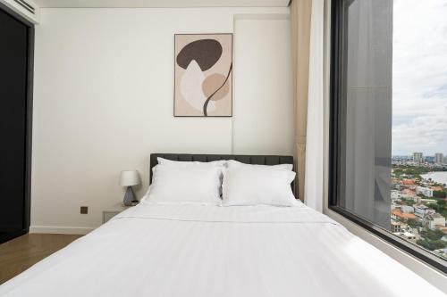 a bedroom with a large white bed and a window at Lumiere Riverside Heera Stay Apartment in Ho Chi Minh City
