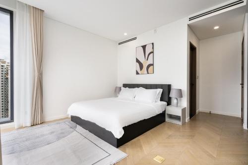 a bedroom with a white bed and a large window at Lumiere Riverside Heera Stay Apartment in Ho Chi Minh City