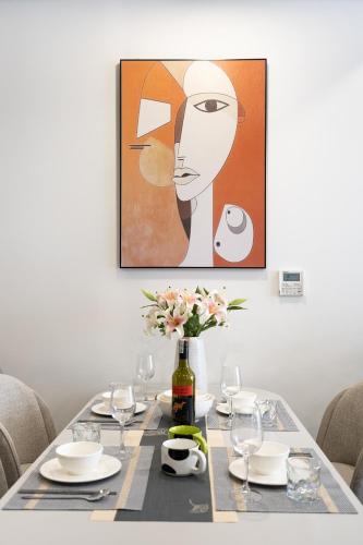 a dining room table with a painting of a woman at Lumiere Riverside Heera Stay Apartment in Ho Chi Minh City