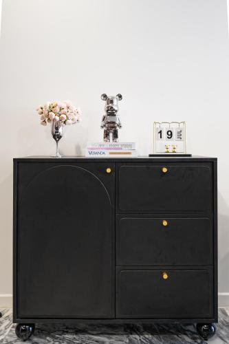 a black dresser with a clock on top of it at Lumiere Riverside Heera Stay Apartment in Ho Chi Minh City