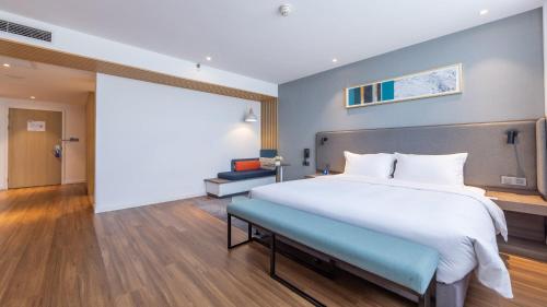 a large bed with a blue bench in a bedroom at Holiday Inn Express Chengdu Wuhou New City by IHG in Chengdu