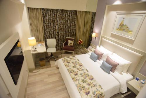a hotel room with a large bed and a desk at Efcee Sarovar Premiere Bhavnagar in Bhavnagar