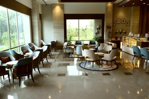 a waiting room with chairs and tables and windows at Efcee Sarovar Premiere Bhavnagar in Bhavnagar