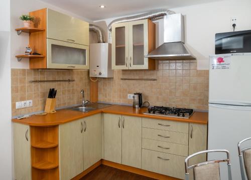 a kitchen with wooden cabinets and a white refrigerator at Lotos for You Apartments in Mykolaiv