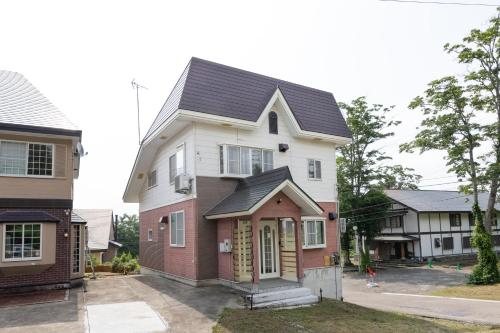 a house with a black roof on a street at Forest and Stars Akakura Sauna in Myoko