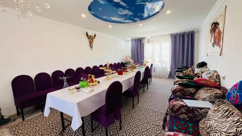 a dining room with a long table and purple chairs at Mira Guest House in Kyzart