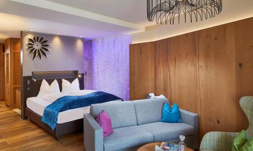 a bedroom with a bed and a couch at Sporthotel Ellmau in Tirol in Ellmau