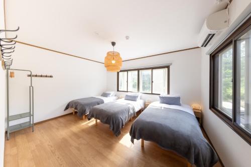 three beds in a room with windows at Forest and Stars Akakura Sauna in Myoko