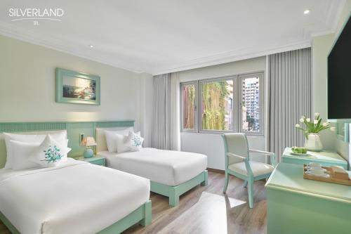 a hotel room with two beds and a chair at Silverland Sil Hotel in Ho Chi Minh City