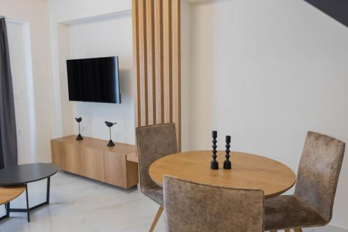 a dining room with a table and chairs and a television at Calma Luxury Suites in Paralia Dionysiou