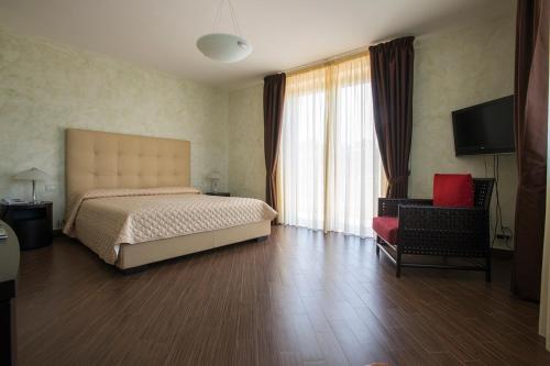 um quarto com uma cama, uma cadeira e uma televisão em Radici Resort em Mirabella Eclano