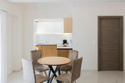 a kitchen with a wooden table and chairs at Calma Luxury Suites in Paralia Dionysiou