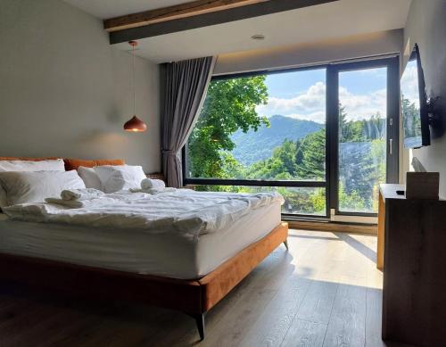 a bedroom with a large bed with a large window at Celest Boutique Urban Hideaway in Braşov