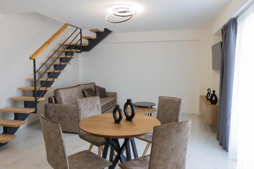 a dining room with a table and chairs and a staircase at Calma Luxury Suites in Paralia Dionysiou