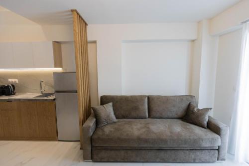 a couch sitting in a living room with a kitchen at Calma Luxury Suites in Paralia Dionysiou