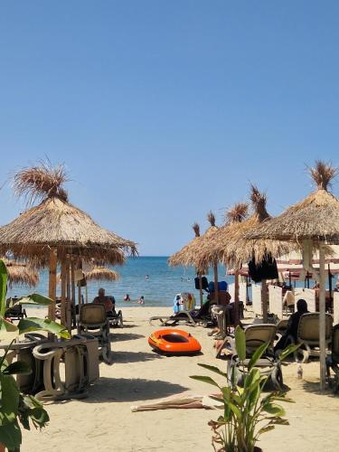a beach with chairs and straw umbrellas and the ocean at Joel Family Apartment's Golem Center in Golem