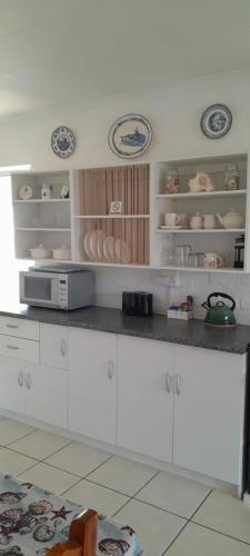 a kitchen with white cabinets and a counter top at Our Little House in Franskraal