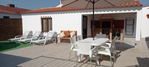 a patio with a white table and chairs and an umbrella at Murta's Home in Cadaval