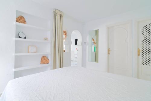 a white bedroom with a white bed and white shelves at Riad Salt Pool Bliss Apartamentos in Torremolinos