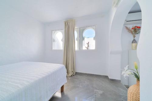 a white bedroom with a bed and two windows at Riad Salt Pool Bliss Apartamentos in Torremolinos
