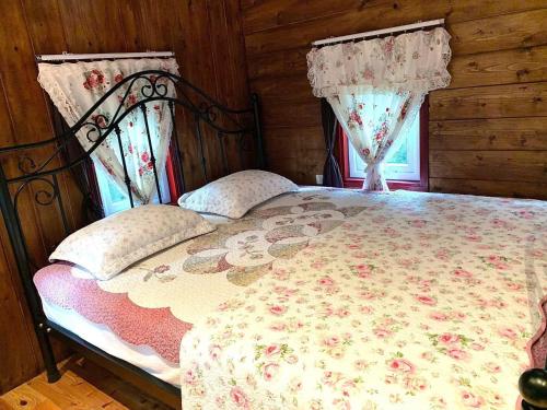 a bedroom with a bed with a floral bedspread and two windows at Khu nghỉ dưỡng Ba Hạt Dẻ in Sóc Sơn